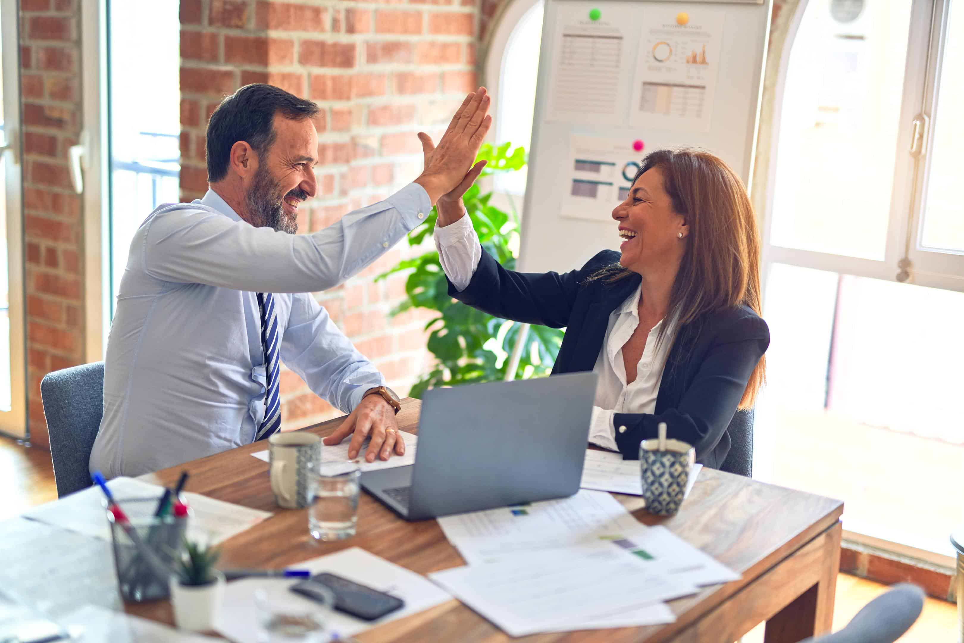 Men in business environment high-fiving woman because Managed WordPress hosting is so awesome.